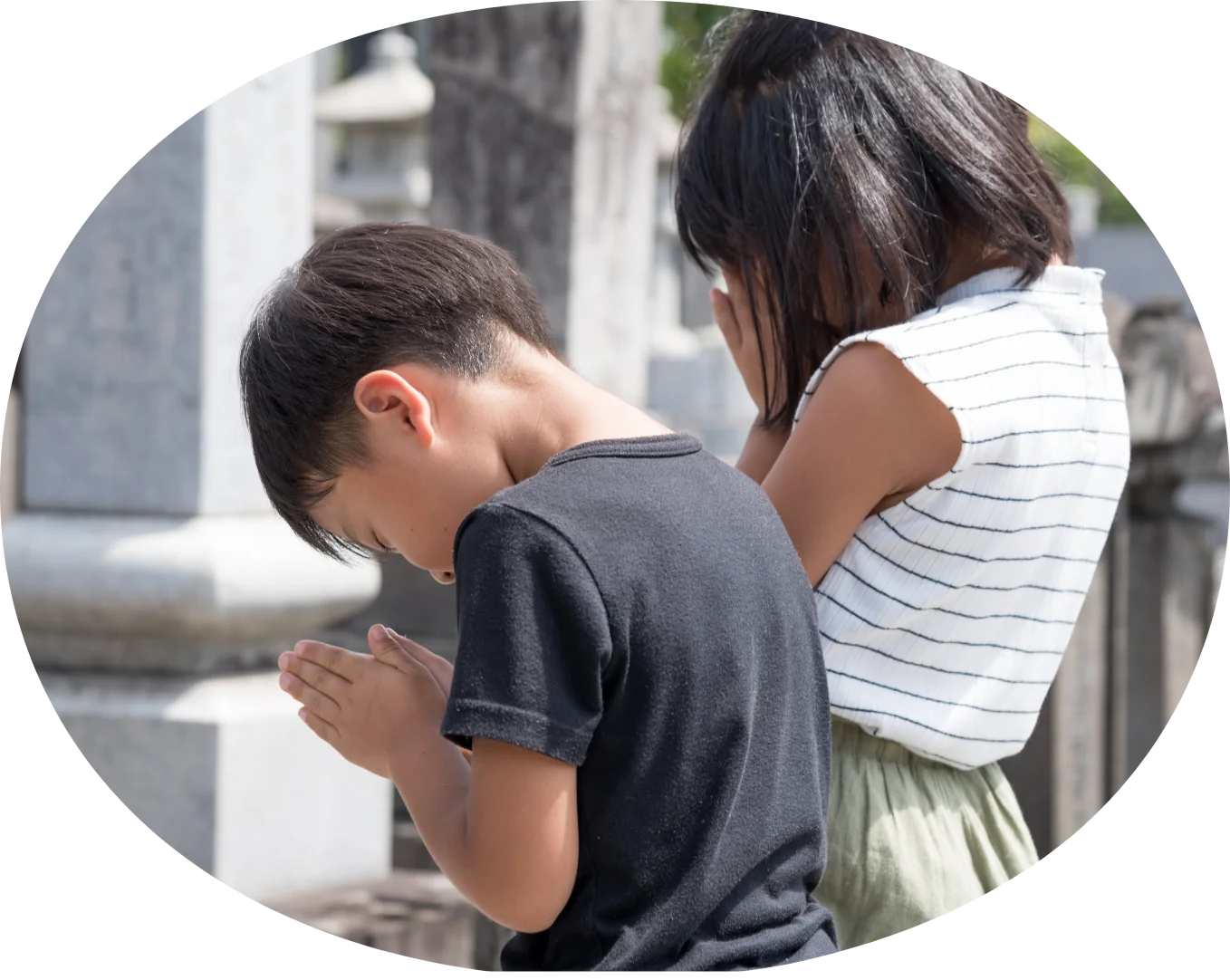 お墓参りで手を合わせる子どもたち